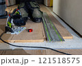 Person Using Circular Saw and Guide Rail for Flooring Installation 121518575