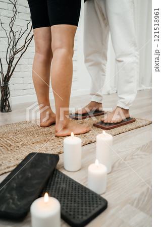 A girl helps a man to stand on nails. Sadhu board. Pleasant atmosphere white candles relaxation. Concept on healthy lifestyle. 121518961