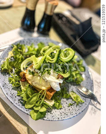 Green salad with poached egg on a toast and mozzarella cheese on a plate in restaurant Green salad with poached egg on a toast and mozzarella cheese on a plate in restaurant 121519339