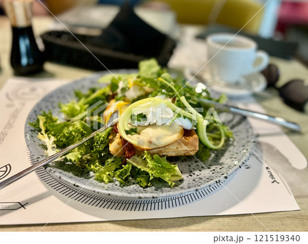Green salad with poached egg on a toast and mozzarella cheese on a plate in restaurant Green salad with poached egg on a toast and mozzarella cheese on a plate in restaurant 121519340