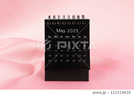 Black desk calendar for May 2025 on a pink silk textile background. Black desk calendar for May 2025 on a pink silk textile background. 121519428