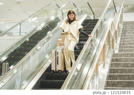 空港に到着しエスカレーターからか降りてくる女性 空港に到着しエスカレーターからか降りてくる女性 121520635
