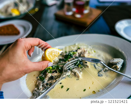 Fried Golden trout fish with lemon and herbs in a white plate on a wooden table at the restaurant in Ukraine 121521421