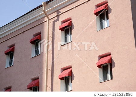 classic-style historic pink house with red awnings on windows. sunny day. stylish architecture 121522880