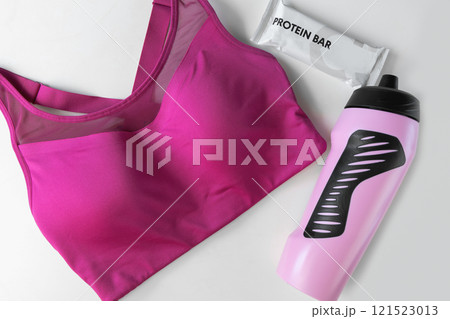Concept of sports lifestyle. Flat lay sports top bra, drinking bottle for water and protein diet bar Concept of sports lifestyle. Flat lay sports top bra, drinking bottle for water and protein diet bar 121523013
