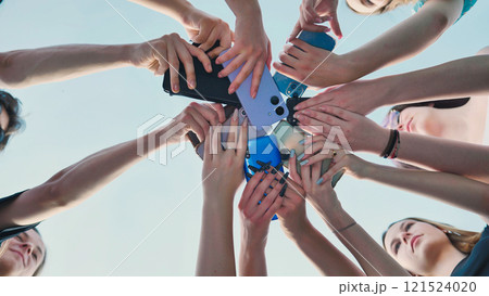 High school students forming a circle with their smartphones, representing togetherness, sharing, and summer memories High school students forming a circle with their smartphones, representing togetherness, sharing, and summer memories 121524020