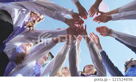 Students celebrating last day of school, wearing sashes and white shirts, arms raised in unity under blue sky. Joyful achievement and hope for future Students celebrating last day of school, wearing sashes and white shirts, arms raised in unity under blue sky. Joyful achievement and hope for future 121524056
