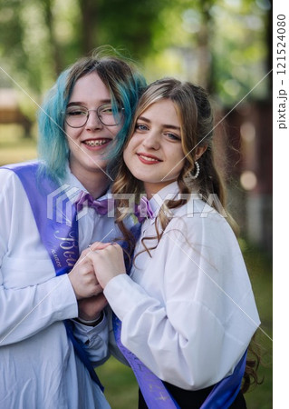 Two joyful female graduates commemorate their final day of school, holding hands in a park and looking ahead to a promising future Two joyful female graduates commemorate their final day of school, holding hands in a park and looking ahead to a promising future 121524080