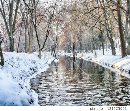 Breathtaking landscape in city park with snowy trees and beautiful reflection in frozen river. Breathtaking landscape in city park with snowy trees and beautiful reflection in frozen river. 121525991