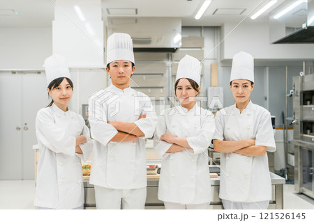 厨房・キッチンに立つコックコート姿の調理師・シェフ・コックの男女 121526145
