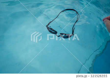 プールで外れたゴーグルを拾おうと手を伸ばす 121526355
