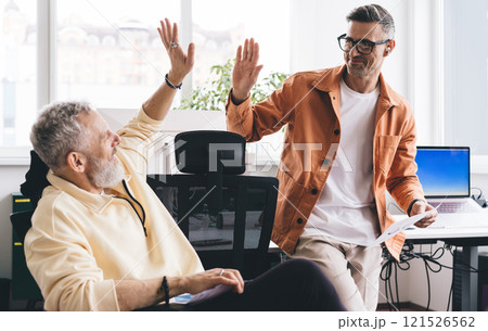 Caucasian male entrepreneurs with documents giving five as deal agreement during work day in office entreprise Caucasian male entrepreneurs with documents giving five as deal agreement during work day in office entreprise 121526562
