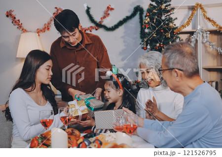 Portrait of Asian family exchanging presents during christmas at home. Attractive happy people holding gift box, celebrate holiday thanksgiving, xmas eve tradition in living room in house together. 121526795