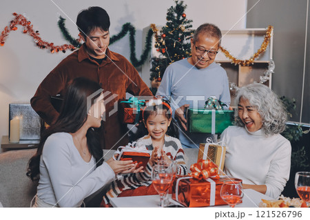 Portrait of Asian family exchanging presents during christmas at home. Attractive happy people holding gift box, celebrate holiday thanksgiving, xmas eve tradition in living room in house together. 121526796