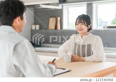 契約書・同意書の説明を聞く主婦と説明する作業着姿の営業マンの男性 契約書・同意書の説明を聞く主婦と説明する作業着姿の営業マンの男性 121530368