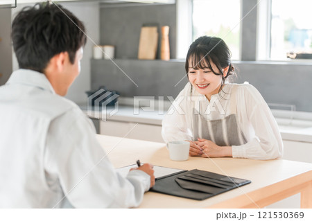 契約書・同意書の説明を聞く主婦と説明する作業着姿の営業マンの男性 121530369
