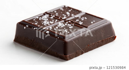 A closeup of a dark rich chocolate square partially melted with a sprinkle of sea salt on top exuding a decadent sheen and inviting texture.. 121530984