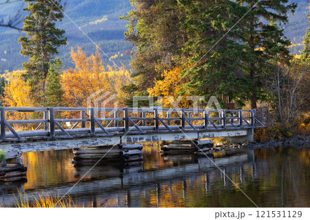 Wooden bridge across the lake to the little island in mountains. 121531129