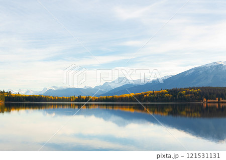 Tranquil lake waters at the mountain foot in autumn forest. 121531131