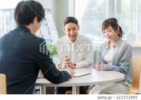 ショールーム・商談スペースで話を聞く夫婦と接客するビジネスマン ショールーム・商談スペースで話を聞く夫婦と接客するビジネスマン 121531805