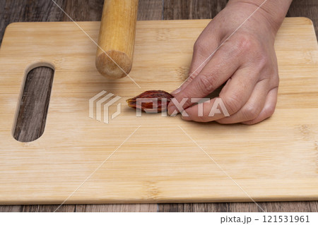 クチナシの実を麺棒で叩いて割る　きんとんを作る 121531961