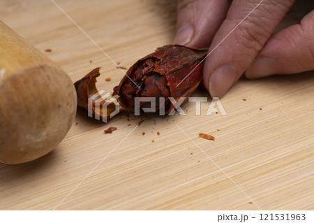 クチナシの実を麺棒で叩いて割る　きんとんを作る 121531963