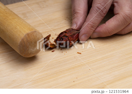 クチナシの実を麺棒で叩いて割る　きんとんを作る 121531964