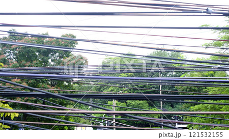 Electric wire pattern in Thailand residential area with green tree background 121532155