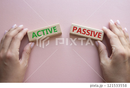 Active or Passive symbol. Concept word Active or Passive on wooden blocks. Businessman hand. Beautiful pink background. Business and Active or Passive concept. Copy space 121533558
