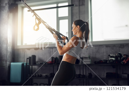 Fitness enthusiast using TRX training in a gym to enhance performance, strength, and wellbeing 121534179