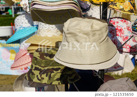 Colorful hats displayed at a vibrant outdoor market on a sunny day Colorful hats displayed at a vibrant outdoor market on a sunny day 121535650