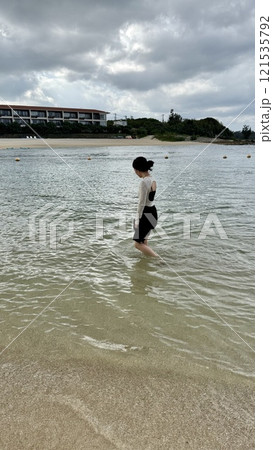 沖縄瀬良垣島の海で足だけ入って遊んでいる女性 121535792