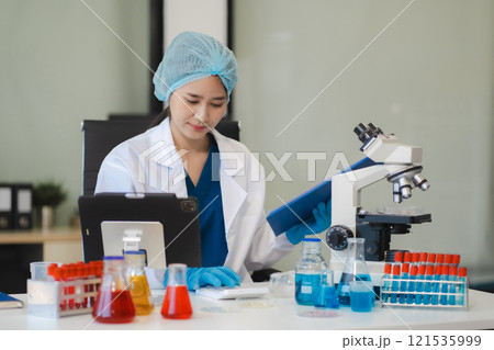 Doctor writes a note and uses a calculator to calculate expenses. 121535999