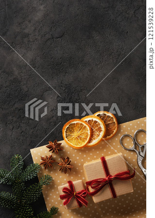 Wrapping supplies for Christmas and New Year gifts. Craft paper, scissors, dried orange, anise stars, spruce branch on dark background. Place for your text. 121539228