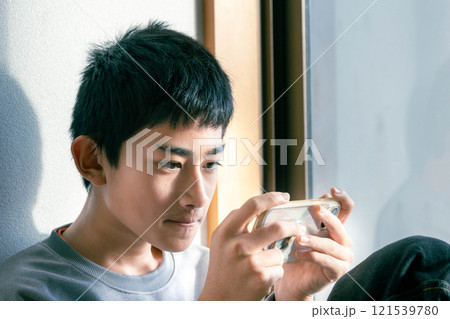 窓際でスマホを操作する男性 窓際でスマホを操作する男性 121539780