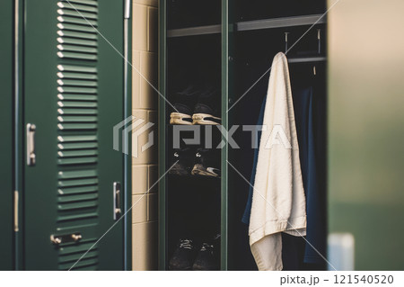 Open locker with towel and running shoes in gym changeroom 121540520