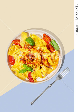 Tagliatelle or pappardelle pasta with tomato sauce, basil and parmesan cheese in a plate  121542319