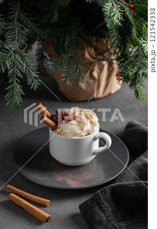 Hot chocolate with whipped cream, cinnamon and anise in a mug on a plate on a on a dark background Hot chocolate with whipped cream, cinnamon and anise in a mug on a plate on a on a dark background 121542338