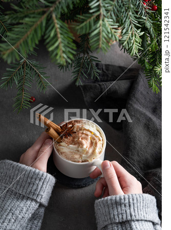 Cup of hot chocolate with whipped cream, cinnamon and anise in hands in gray sweater Cup of hot chocolate with whipped cream, cinnamon and anise in hands in gray sweater 121542341