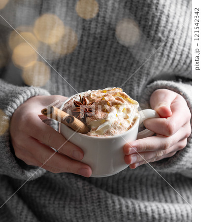 Cup of hot chocolate with whipped cream, cinnamon and anise in hands Cup of hot chocolate with whipped cream, cinnamon and anise in hands 121542342