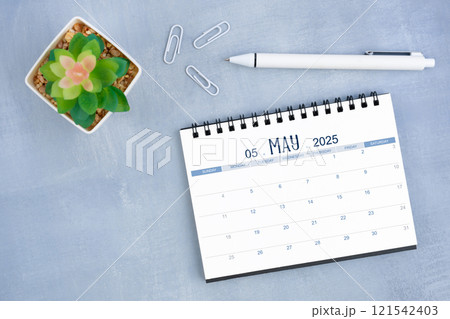 May desk calendar for 2025 year and plant pot with pen on blue cement. May desk calendar for 2025 year and plant pot with pen on blue cement. 121542403