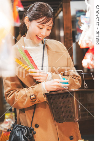 昔ながらの駄菓子屋で懐かしく買い物をする若い女性【撮影協力・お米・駄菓子屋 加賀田米穀店】 121543675