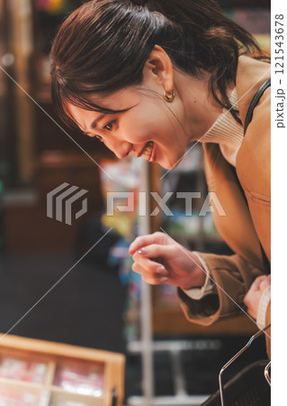 昔ながらの駄菓子屋で懐かしく買い物をする若い女性【撮影協力・お米・駄菓子屋 加賀田米穀店】 121543678