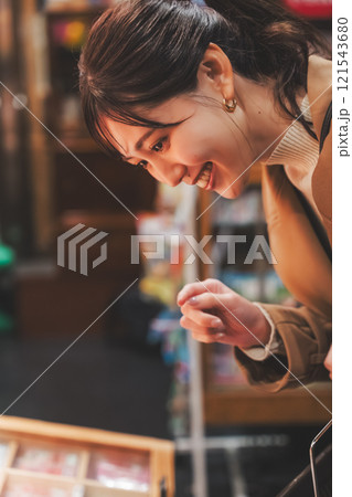 昔ながらの駄菓子屋で懐かしく買い物をする若い女性【撮影協力・お米・駄菓子屋 加賀田米穀店】 昔ながらの駄菓子屋で懐かしく買い物をする若い女性【撮影協力・お米・駄菓子屋 加賀田米穀店】 121543680