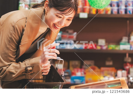 昔ながらの駄菓子屋で懐かしく買い物をする若い女性【撮影協力・お米・駄菓子屋 加賀田米穀店】 121543686