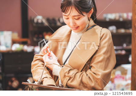 昔ながらの駄菓子屋で懐かしく買い物をする若い女性【撮影協力・お米・駄菓子屋 加賀田米穀店】 121543695