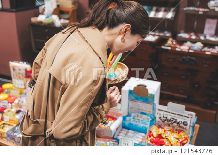 昔ながらの駄菓子屋で懐かしく買い物をする若い女性【撮影協力・お米・駄菓子屋 加賀田米穀店】 昔ながらの駄菓子屋で懐かしく買い物をする若い女性【撮影協力・お米・駄菓子屋 加賀田米穀店】 121543726
