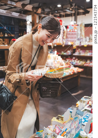 昔ながらの駄菓子屋で懐かしく買い物をする若い女性【撮影協力・お米・駄菓子屋 加賀田米穀店】 121543734