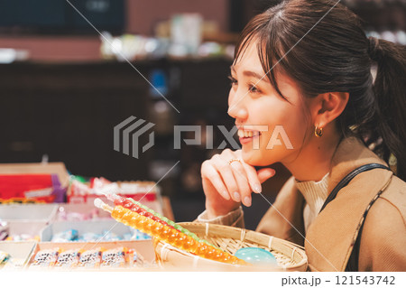 昔ながらの駄菓子屋で懐かしく買い物をする若い女性【撮影協力・お米・駄菓子屋 加賀田米穀店】 121543742