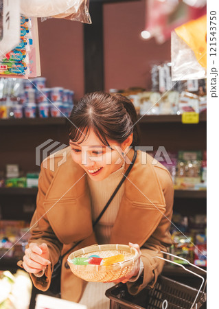 昔ながらの駄菓子屋で懐かしく買い物をする若い女性【撮影協力・お米・駄菓子屋 加賀田米穀店】 121543750